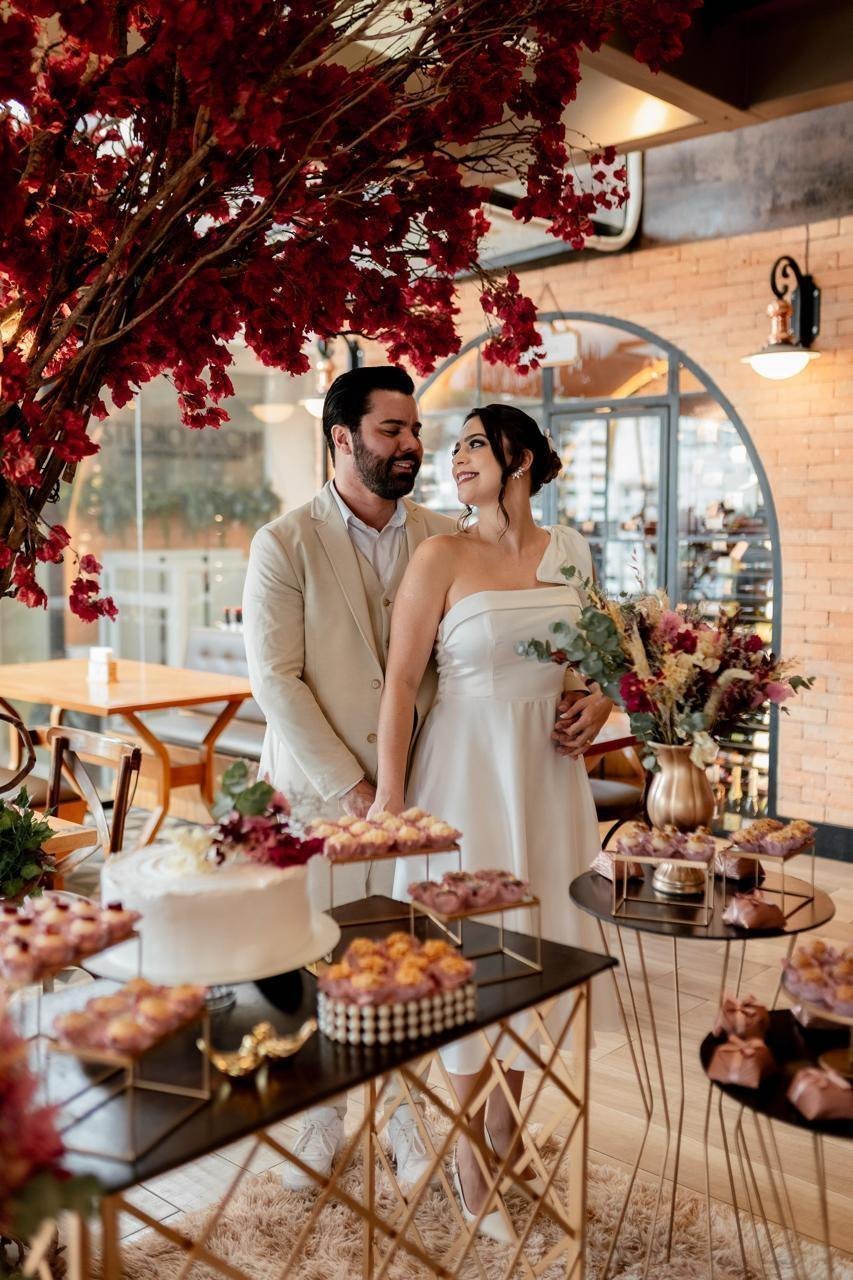 Cerimônia de casamento ao ar livre sob árvores, com corredor de cadeiras e arco verde